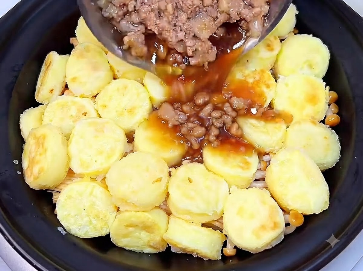 Ugotowana mielona wieprzowina wraz z ciemnym, esencjonalnym sosem wylewana z patelni na warstwę tofu w glinianym garnku.