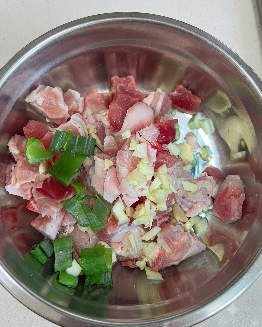 Surowe kawałki boczku wieprzowego w misce połączone z czosnkiem, dymką i czerwoną pastą chili.