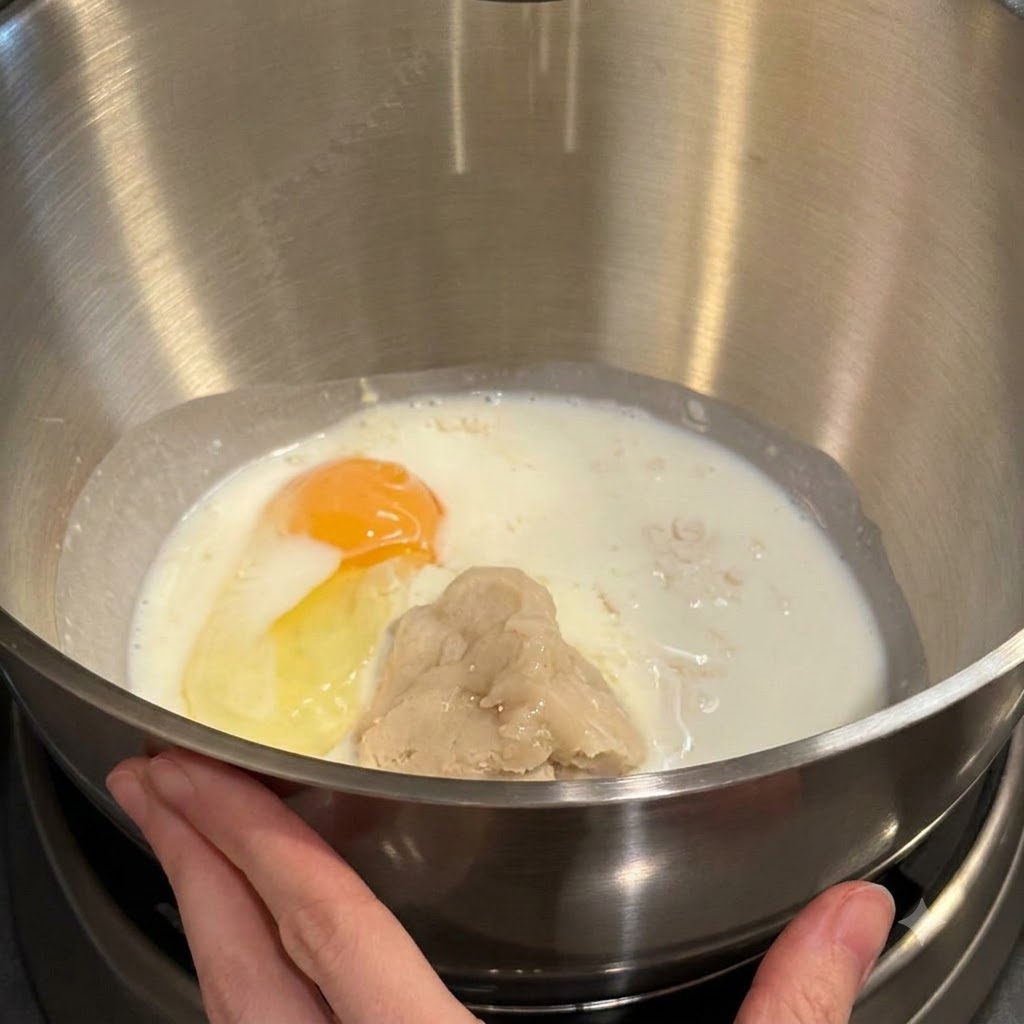 Miska miksera zawierająca mąkę, mleko, żółtko jajka i pastę tangzhong gotowa do miksowania.