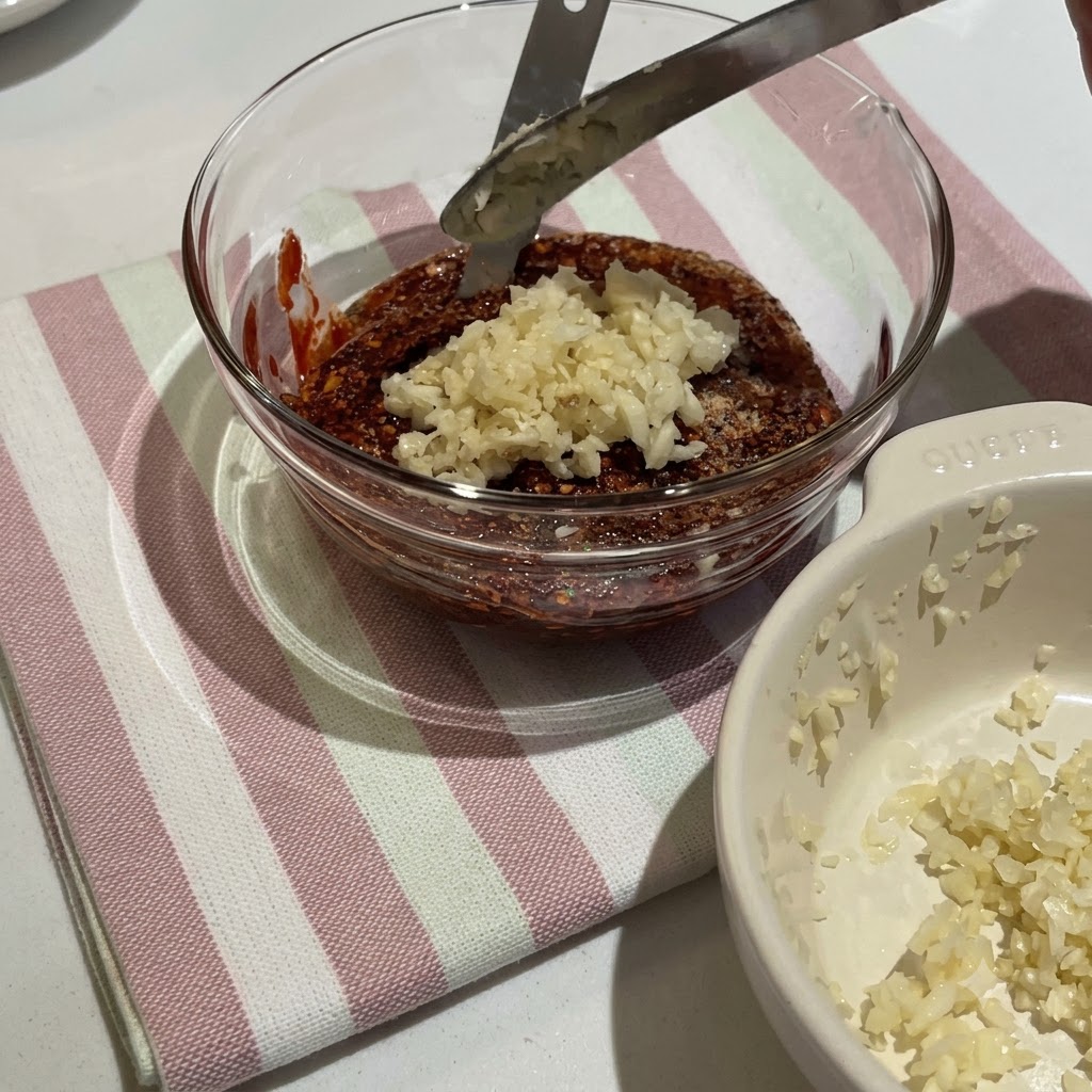 Koreańska pasta chili i różne przyprawy mieszane w szklanej misce, aby utworzyć gęsty czerwony sos.