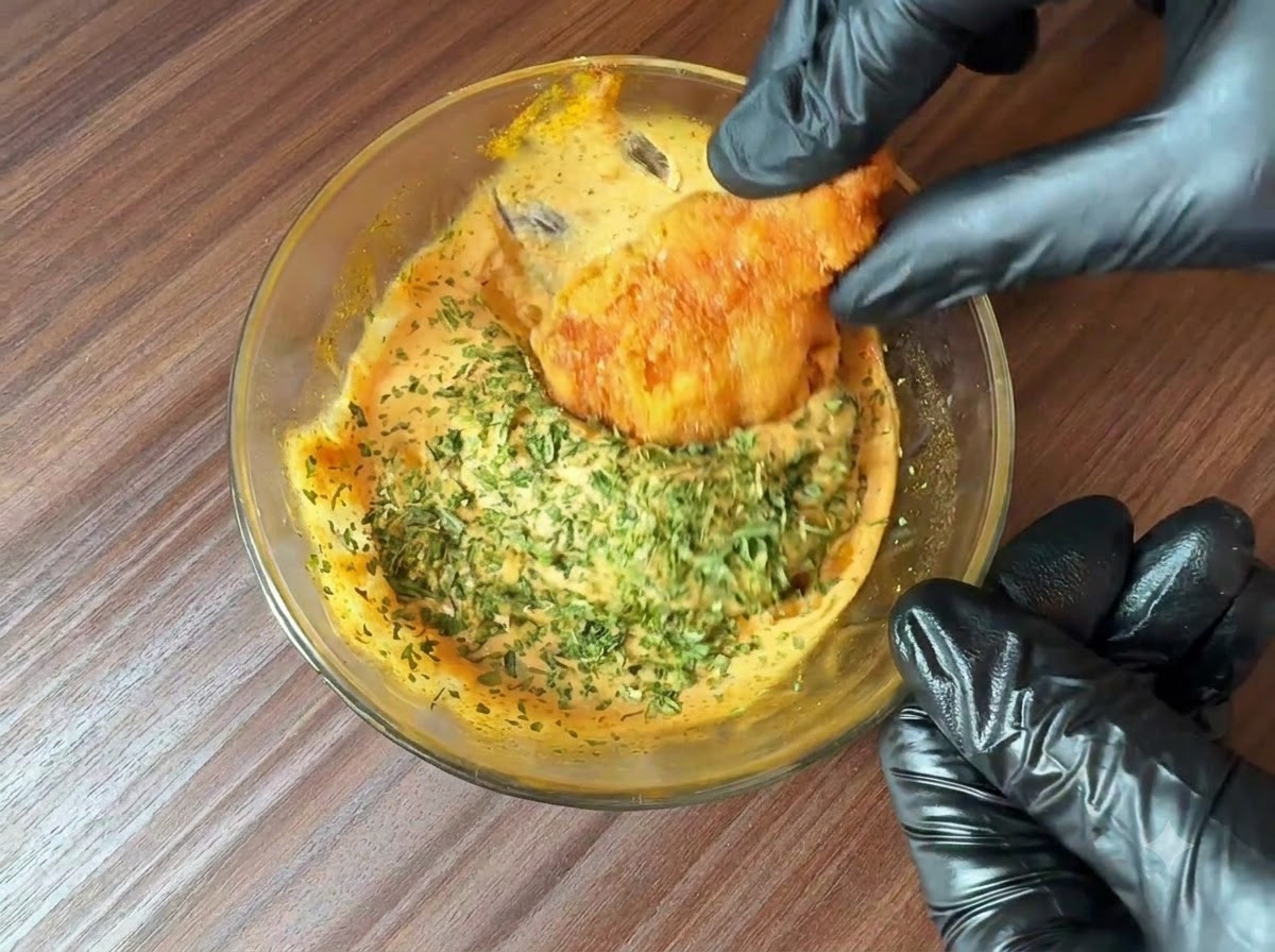 Świeżo posiekana pietruszka posypana na miskę przygotowanego sosu do burgerów, podczas gdy kawałek smażonej potrawy jest w nim maczany.